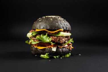Siyah arka planda siyah çörekli lezzetli hamburgerler.