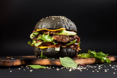 Siyah arka planda siyah çörekli lezzetli hamburgerler.