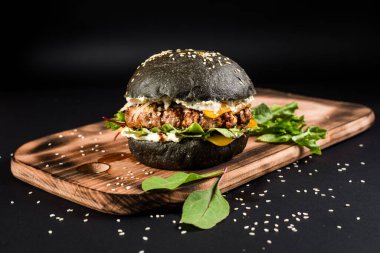 Siyah arka planda siyah çörekli lezzetli hamburgerler.