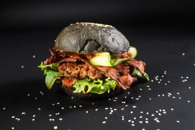 Siyah arka planda siyah çörekli lezzetli hamburgerler.