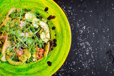 Siyah tahta üzerinde yeşil tabakta karışık sebze salatası.