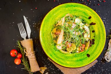 Siyah tahta üzerinde yeşil tabakta karışık sebze salatası.