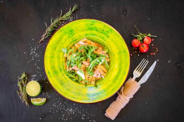 Siyah tahta üzerinde yeşil tabakta peynirli lezzetli makarna.