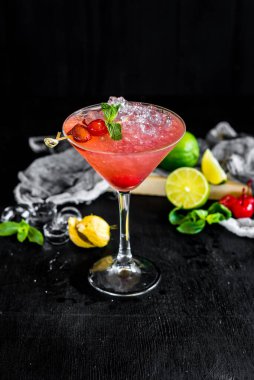 Vişneli pembe kokteyl ve siyah arka planda buz.