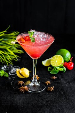 Vişneli pembe kokteyl ve siyah arka planda buz.