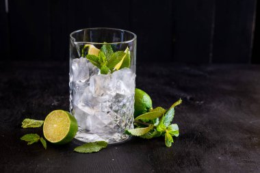 Siyah arka planda buzlu ve naneli kokteyller için büyük bir bardak.
