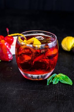 Buzlu kırmızı kokteyl ve siyah arka planda turuncu.