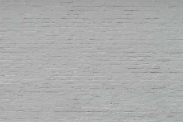 Vieja pared de ladrillo pintado blanco. Fondo blanco con textura de ladrillo agrietado con una gran capa de pintura . — Foto de Stock