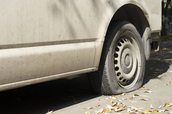 Старый белый фургон на дороге. Спустило колесо осенью с листьями, возле старой ржавой машины . — стоковое фото