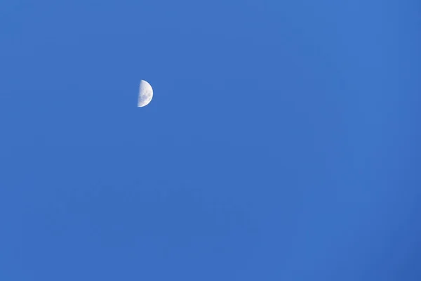 Niebieskie niebo dzienne z połową księżyca. Satelita ziemski na błękitnym niebie. — Zdjęcie stockowe