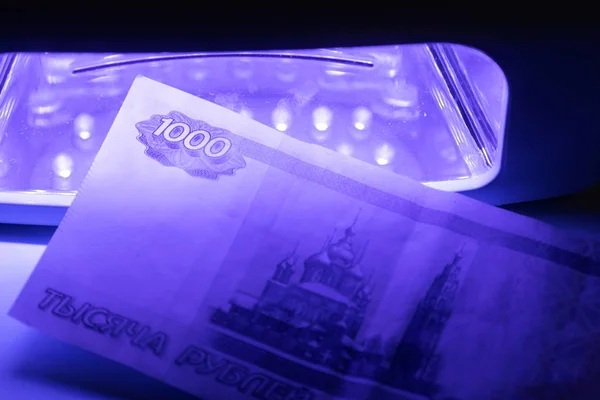 One thousand Russian rubles in infrared light. Check on the detector. Check for fake or genuine. Counterfeiting banknotes, checking at the bank by a cashier of 1000 rubles, by a banking operator. Financial, banking concept.