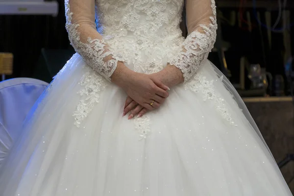 Bride in a white dress with tender freckled hands. Female hands with a wedding ring. Shiny white beautiful dress. Detail of a bride dress closeup.