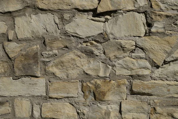 Doku doğal taşın grisi, düz olmayan çatlak taşların beton yüzeyi. Çitle, çimentoyla bağlanmış sarımsı bir duvar. Tasarımcı için özet, arkaplan.