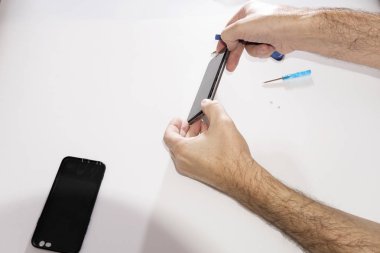 Phone repair in a service center. Dismantling glass from a mobile phone. Replacing the touchpad matrix of the glass touchpad. Hands repair the phone.