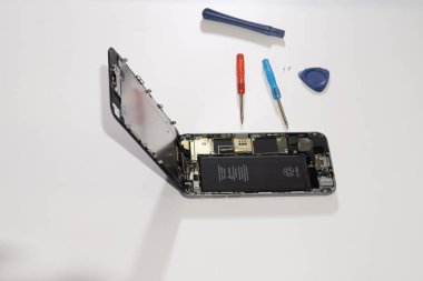 Phone repair in a service center. Replacing the touch matrix of the glass touchpad. Replacing the black battery of the phone. Phone marriage concept.