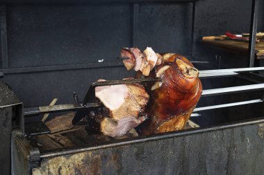 Pork knuckle is fried on a spit. Street grill, fried meat with crispy brown crust. Street food, pieces of meat. Traditional food in the Czech Republic. Prague.