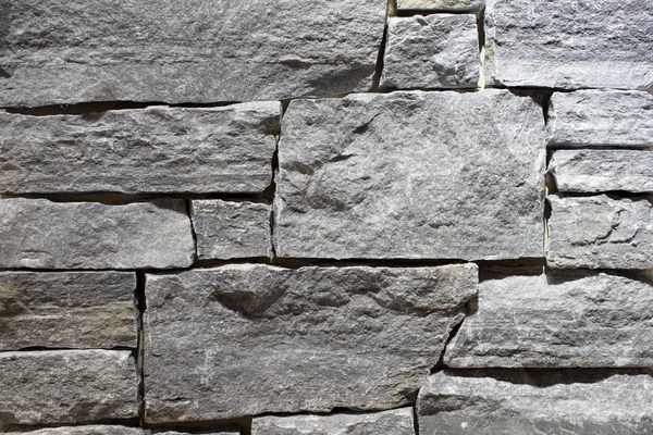 Wall made of natural gray stone. Background of stone blocks. Fence or foundation made of natural stones. Texture for design close-up.