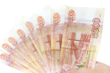 İzole edilmiş beyaz arka planda bir yelpaze içinde bir paket Rus rublesi. Beş bin rublelik banknotlar kırmızıdır. El parayı tutar. Yakın plan..