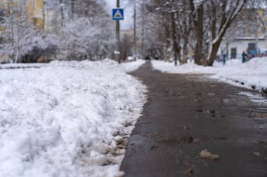 Winter road for pedestrians cleaned from snow. Chemicals pour on a pedestrian path, the snow has melted. Frost, snow fell.