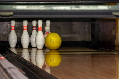 Bowling topu çivilere giden tahta bir patika boyunca yuvarlanıyor. Altın top lobutları deviriyor.