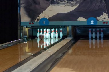 Bowling topu çivilere giden tahta bir patika boyunca yuvarlanıyor. Altın top lobutları deviriyor.