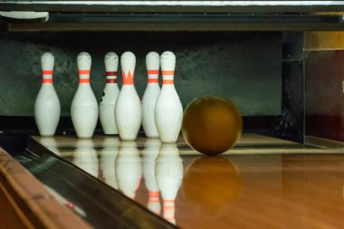 Bowling topu çivilere giden tahta bir patika boyunca yuvarlanıyor. Altın top lobutları deviriyor.