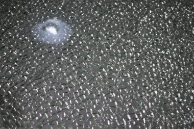 Kırık sertleştirilmiş cam yakın plan. Parçalanmış cam dokusu ve beyaz leke.