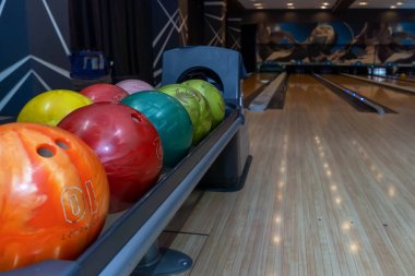 Bowling topları kuyrukta bir tutucuda yatıyor. Renkli toplar ve bowling kulvarı.