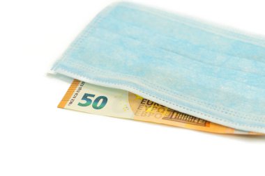Mavi tıbbi maske 50 avroluk banknotun üzerinde yatıyor. Avrupa 'dan maske alma fikri, virüse karşı koruma. İzole edilmiş beyaz arka plan. Yukarıdan görüntüle.