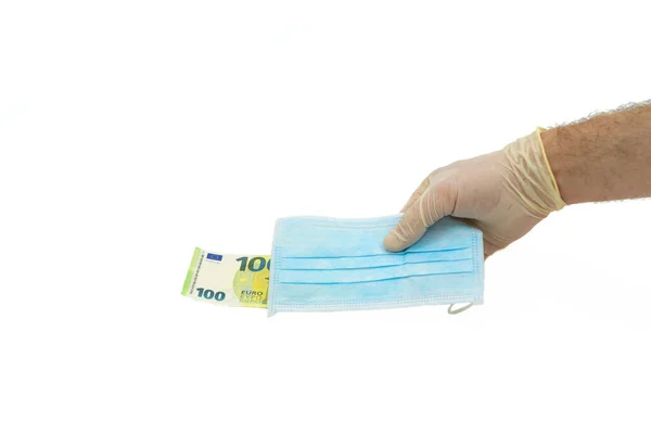 Beyaz koruyucu eldivenli bir el, 100 avro karşılığında mavi bir tıbbi maske veriyor. Avrupa 'dan maske alma fikri, virüse karşı koruma. İzole edilmiş beyaz arkaplan.