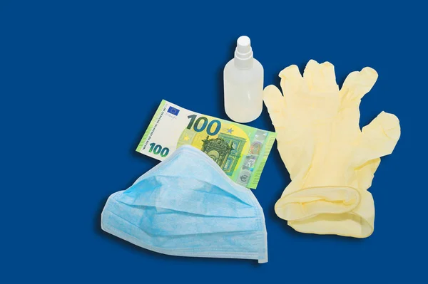 青いマスクは 防腐剤とお金100ユーロと黄色の保護医療用手袋にあります ウイルスに対する保護のためのアイテムを購入するという概念 青の背景 — ストック写真