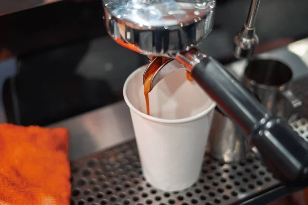 Coffee is poured from a professional coffee machine into a paper Cup to take away. Coffee to go.