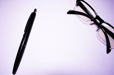 Beyaz zemin üzerinde siyah gözlük ve kalem, yukarıdan çekilmiş, masaüstü