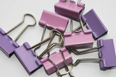 Çok renkli ataçlar beyaz arka plana saçılmış, fotoğraf yukarıdan çekilmiş.