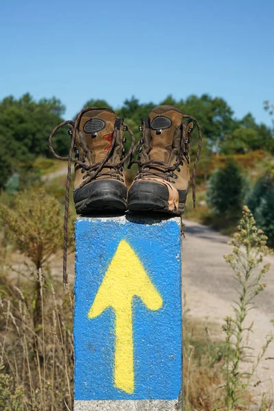 Broken walking shoes on the top of a waymark along the Way of St. James, Spain, Europe