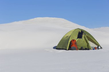 Hiking kış. Güneşli kış dağlarda yeşil çadır.
