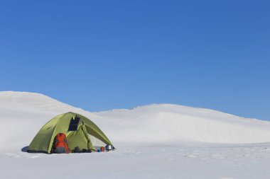 Hiking kış. Güneşli kış dağlarda yeşil çadır.