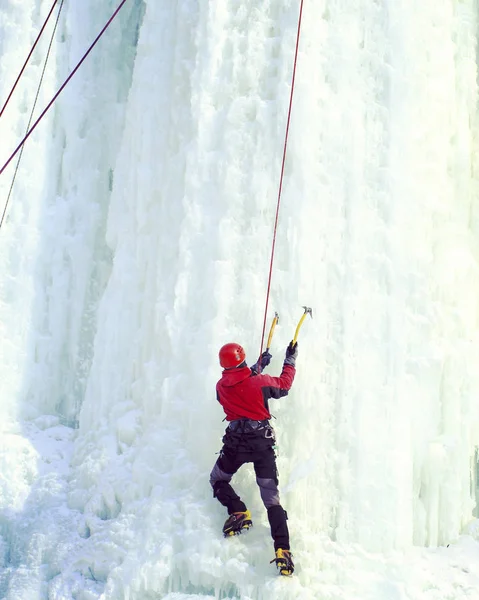 攀冰。男子攀爬的冰冻的瀑布. — 图库照片