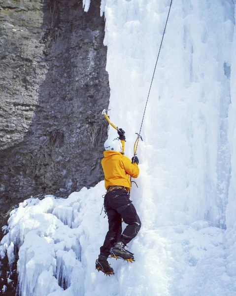 Arrampicata su ghiaccio.Uomo arrampicata cascata congelata . — Foto Stock