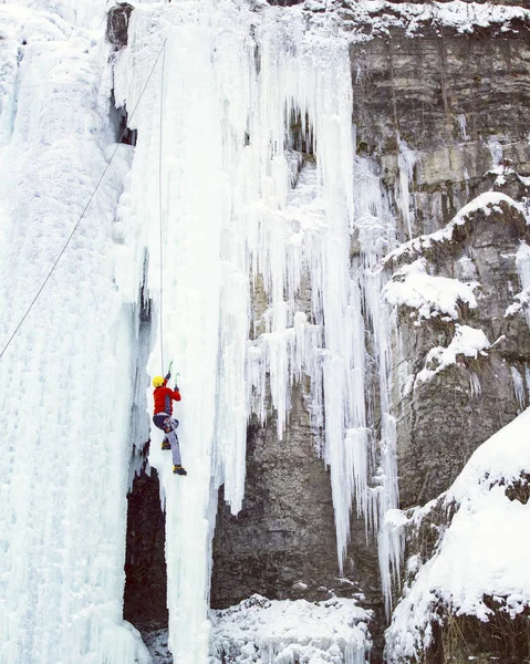 Arrampicata su ghiaccio.Uomo arrampicata cascata congelata . — Foto Stock