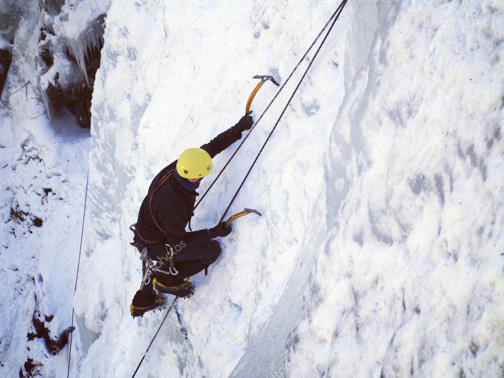 Ice climbing.Man climbing frozen waterfall.