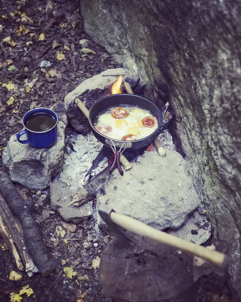 Cucinare la colazione in un falò in un campo estivo . — Foto Stock