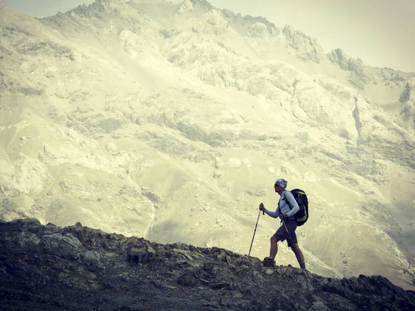 Uomo turista a piedi per le montagne con uno zaino . — Foto Stock