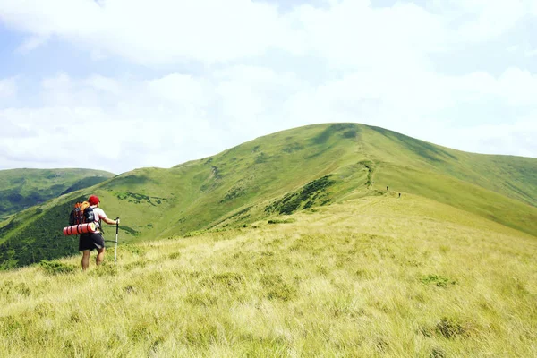 Uomo turista a piedi per le montagne con uno zaino . — Foto Stock