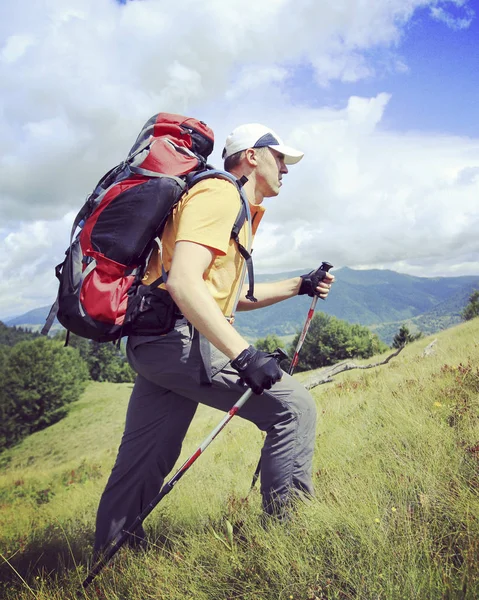 Hombre turista caminando por las montañas con una mochila . — Foto de Stock