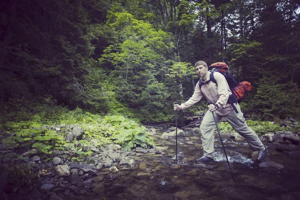 Hombre turista caminando por las montañas con una mochila . — Foto de Stock