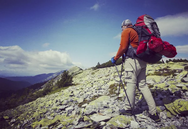 Uomo turista a piedi per le montagne con uno zaino . — Foto Stock