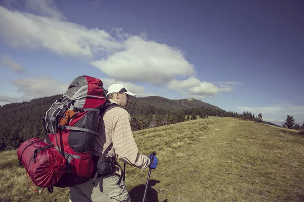 Uomo turista a piedi per le montagne con uno zaino . — Foto Stock