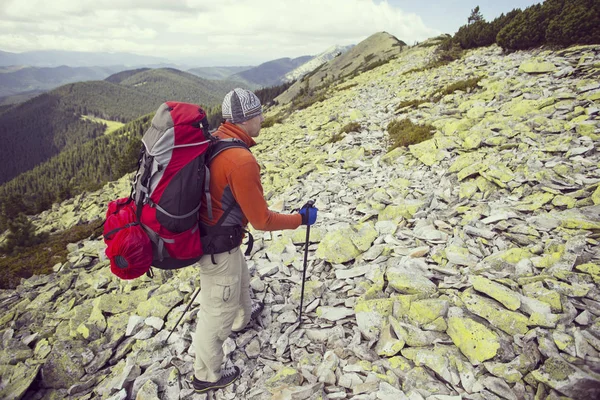 Uomo turista a piedi per le montagne con uno zaino . — Foto Stock