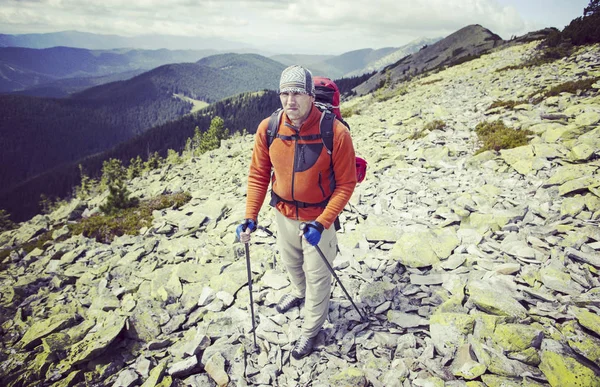 Uomo turista a piedi per le montagne con uno zaino . — Foto Stock